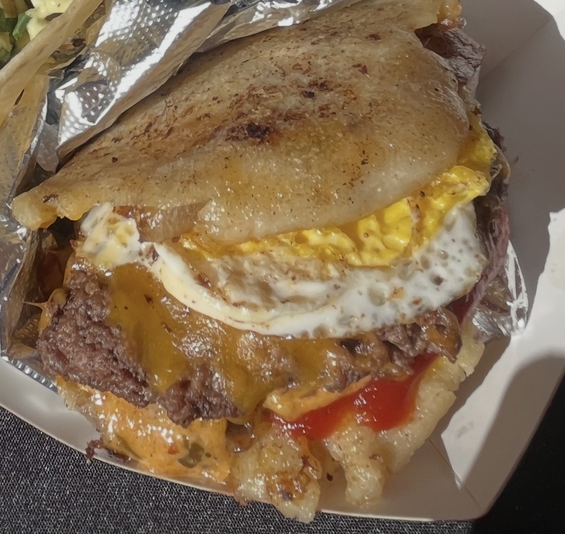 Hangover burger with fried egg, bacon, onion jam, cheddar and burger sauce served on an arepa