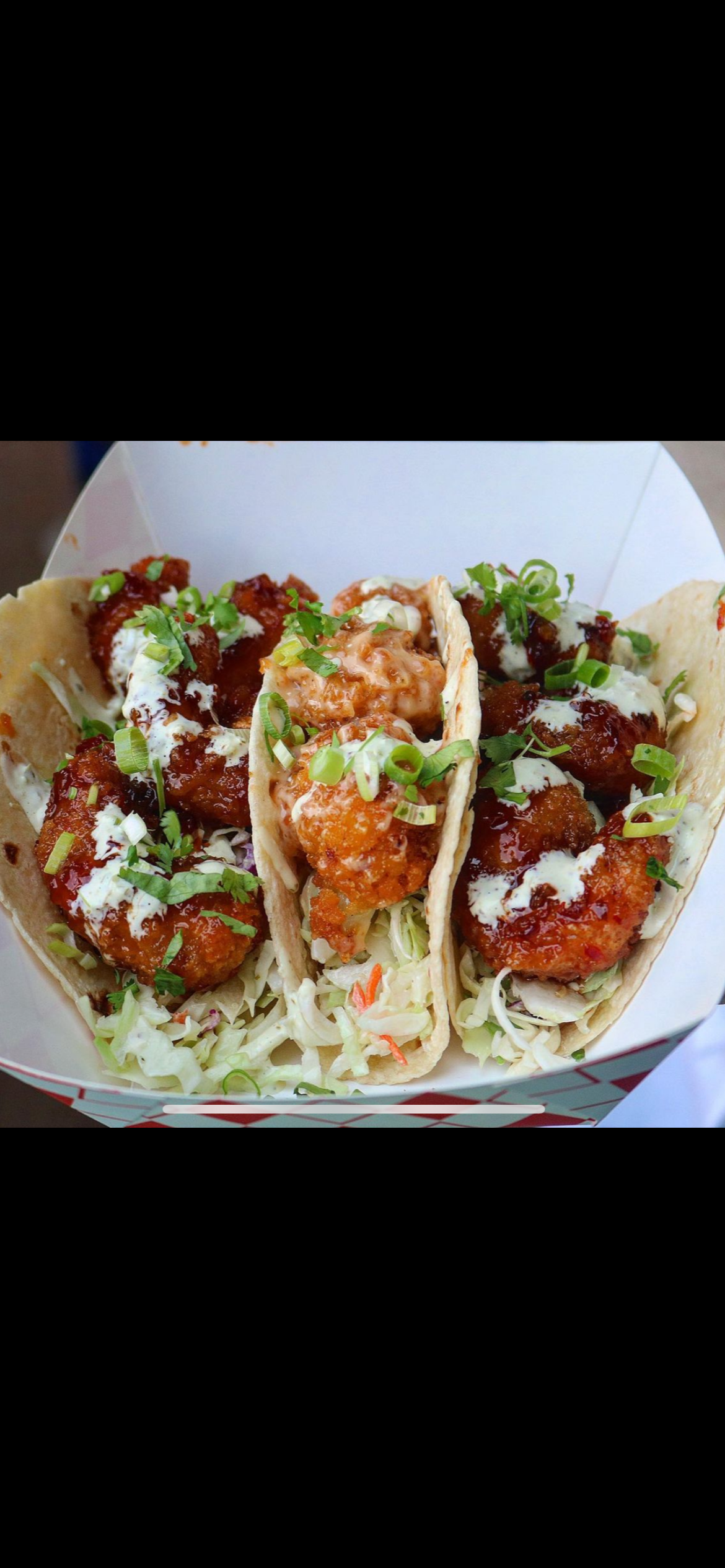 Three tacos filled with honey sriracha shrimp and Bang Bang cauliflower, topped with slaw and scallion